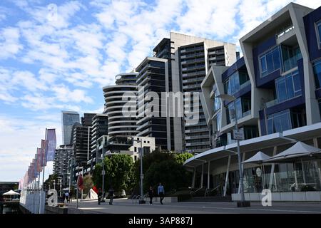 Eine Reihe von modernen Wohngebäuden am Wasser in Melbournes Docklands, an einem sonnigen Tag mit Menschen auf dem Fußweg darunter Stockfoto