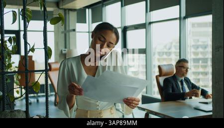Geschäftsfrau liest Dokumente während eines Telefongesprächs Stockfoto