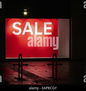 Beleuchtetes rotes Schaufenster mit „Sale“-Schriftzug Stockfoto