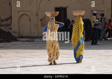 Jaipur, Rajasthan, Indien, Asien, zwei Frauen in bunten Saris tragen Körbe auf dem Kopf durch einen Innenhof, Nordindien, Asien Stockfoto