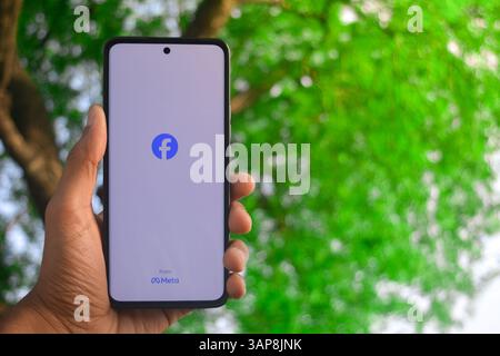 TIKAMGARH, MADHYA PRADESH, INDIEN - 10. APRIL 2025: Mann hält Handy mit App facebook auf dem Bildschirm. Stockfoto