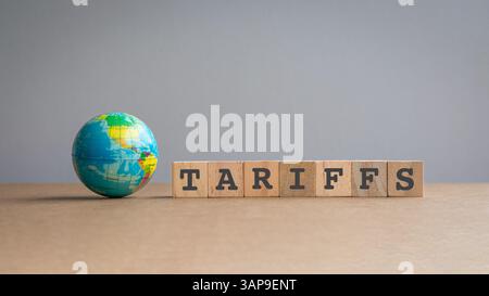 Miniaturkugel neben Nachricht, Tarriffs auf quadratischen Holzblöcken. Stockfoto