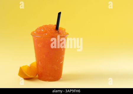 Orangefarbener Slushie auf gelbem Hintergrund. Stockfoto