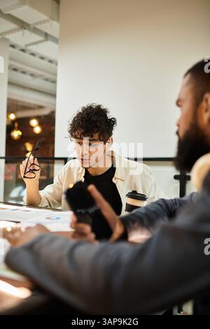 Zwei Fachleute diskutieren während sie Materialien an einem modernen Arbeitsplatz durcharbeiten. Stockfoto