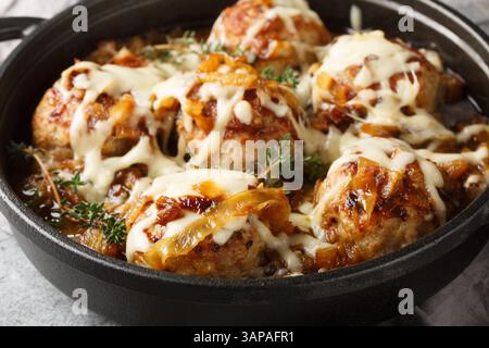 Gebackene französische Zwiebelfleischbällchen mit karamelisierten Zwiebeln und Gruyerekäse in der Pfanne auf dem Tisch. Horizontal Stockfoto