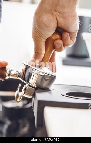 Der Barista stampft Kaffeesatz im Portafilter für die Espresso-Zubereitung aus nächster Nähe Stockfoto