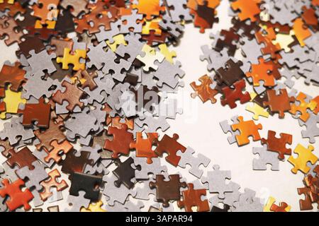 Rote, orange, gelbe, braune und schwarze Puzzles, die auf der weißen Oberfläche verstreut sind Stockfoto