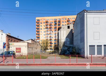 Żyrardów, Polen April 2025. Eine lebhafte urbane Szene, in der ein modernes Apartmenthaus im Kontrast zu älteren, verwitterten Bauten in Żyrardów steht. Stockfoto