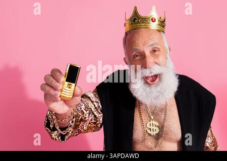 Porträt des wohlhabenden Großvaters tragen goldene Handyabnutzung Diadem Leopardenmantel isoliert auf rosa Hintergrund Stockfoto