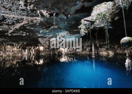 Eine faszinierende Cenote tief unter der Erde auf der Halbinsel Yucatán, Mexiko. Klares blaues Wasser reflektiert die Stalaktiten und Kalksteine in Kin Ha Stockfoto