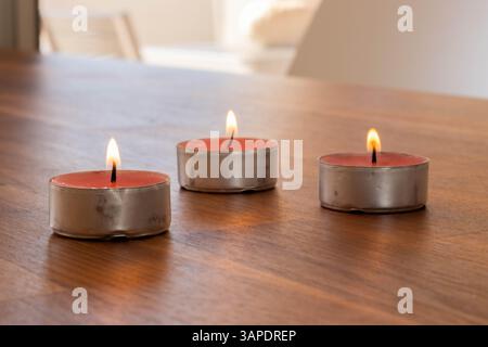 Drei Teelichter brennen auf Holztisch Stockfoto