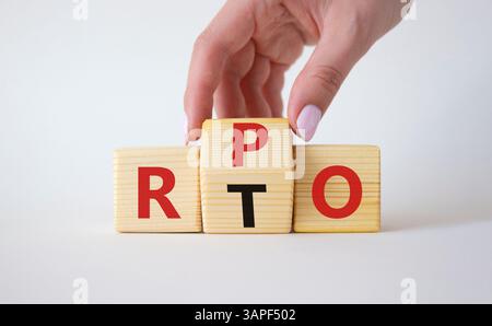 RPO vs. RTO-Symbol. Geschäftsmann-Hand dreht Holzwürfel und ändert das Wort RTO in RPO. Schöner weißer Hintergrund. Geschäftskonzept. Kopierbereich Stockfoto