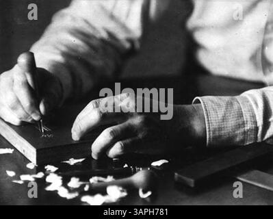 Dieses Foto, aufgenommen in Berea, zeigt John Jacob Niles, eine bekannte Figur, die einen Holzblock schneidet. Das Bild zeigt den Schnittpunkt von Handwerkskunst und Porträtkunst, der in der Sammlung der Bibliotheken der Universität von Oregon aufbewahrt wurde. Stockfoto