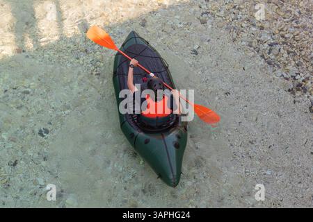 Blick Auf Den Fluss Kajak Aus Der Vogelperspektive. Kaukasischer Sportsman im grünen Kajak paddeln auf dem malerischen Fluss Soca, Bovec, Slowenien Stockfoto