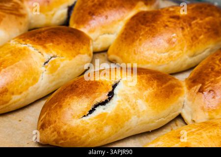 Gebackene Brötchen gefüllt mit Johannisbeermarmelade auf Pergamentpapier. Stockfoto
