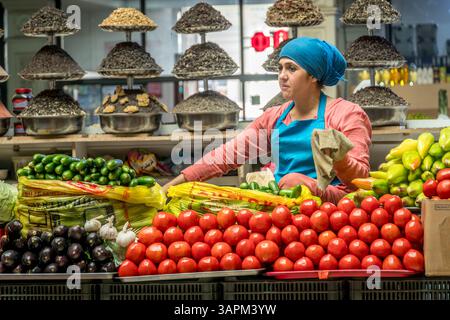 Eine Frau verkauft lebendige Tomaten, Gurken und frisches Gemüse auf dem Dushanbe-Markt in Tadschikistans Hauptstadt Duschanbe. Stockfoto