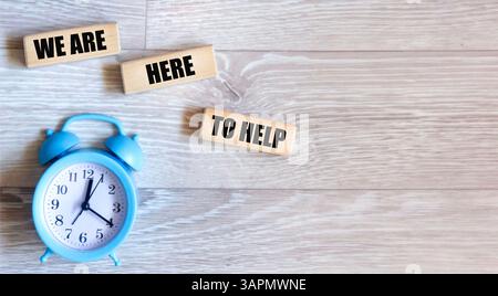 Wir sind hier, um zu helfen, ein Symbol. Konzeptionelle Wörter, die wir auf Holzblöcken schreiben können. Platz zum Kopieren. Stockfoto