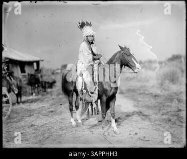 Dieses Foto zeigt einen Ureinwohner im Kostüm auf dem Pferd, der traditionelle Ureinwohner-Kleidung und Reiterkultur zeigt. Stockfoto