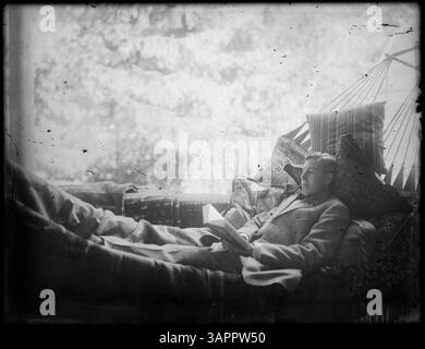 Ein Mann ist in einer Hängematte abgebildet, die auf einem historischen Foto von Lee Moorhouse aufgenommen wurde. Das Bild ist Teil der Lee Moorhouse-Sammlung der University of Oregon Libraries. Stockfoto