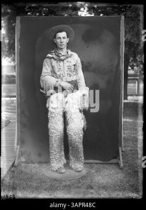Dieses abendfüllende Porträt von Lee Moorhouse fängt Glen Bushee ein, einen Cowboy, der in traditioneller Pose steht. Das Foto gibt Einblicke in die Kleidung und Identität der Cowboys im frühen 20. Jahrhundert. Stockfoto