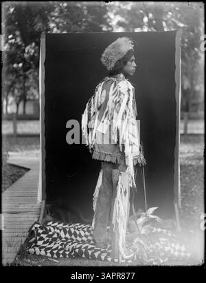 Dieses Foto zeigt einen Yakima-Indianer in verschiedenen Regalias, aufgenommen von Lee Moorhouse. Das Bild ist Teil der Lee Moorhouse-Sammlung der University of Oregon Libraries. Stockfoto