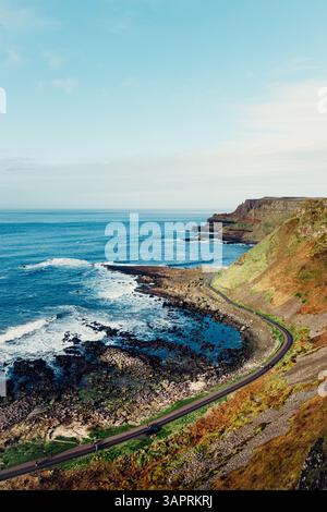 Moody Aerial View of Giant’s Causeway mit Wellen, die in die Felsen stürzen und Menschen herumlaufen Stockfoto