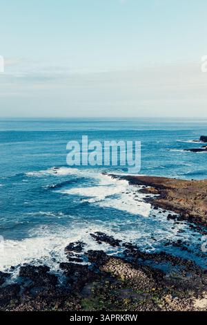 Moody Aerial View of Giant’s Causeway mit Wellen, die in die Felsen stürzen und Menschen herumlaufen Stockfoto