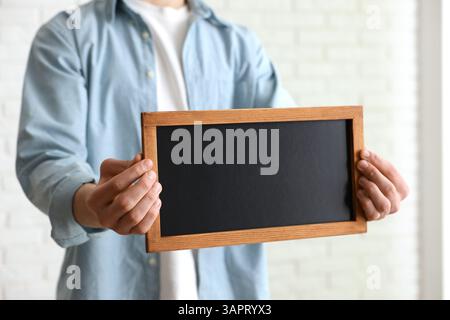 Mann hält leere kleine Tafel drinnen, Nahaufnahme Stockfoto