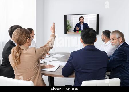 Redner, der über Online-Videochat an der Vorlesung teilnimmt. Publikum im Konferenzraum mit Fernseher Stockfoto