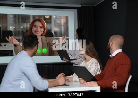 Redner, der über Online-Videochat an der Vorlesung teilnimmt. Publikum und Trainer im Konferenzraum mit Projektionsleinwand Stockfoto