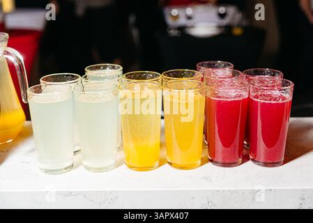 Farbenfrohe Vielfalt an Säften in hohen Gläsern auf einer Theke, bereit für eine Veranstaltung oder Party mit Catering. Stockfoto