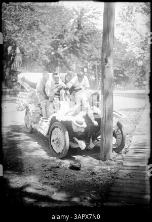 Dieses Foto zeigt eine Autoparade in Pendleton, Oregon. Fünf Männer in einem Auto sehen sich scherzhaft an, als ob das Fahrzeug gegen einen Baum gestürzt ist. Das Auto ist mit Baumwoll- oder weißen Rosetten dekoriert, was den unbeschwerten Charakter der Szene unterstreicht. Stockfoto