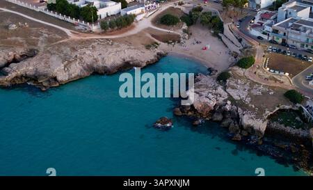 Blick aus der Vogelperspektive auf einen kleinen urbanen Strand mit felsiger Küste und türkisfarbenem Wasser Stockfoto