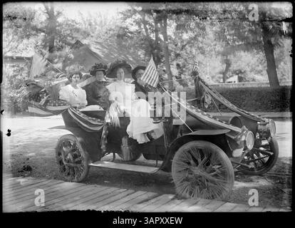 Lee Moorhouses Foto zeigt eine Autoparade in Pendleton, Oregon, mit einem Mann und drei Frauen in einem Auto, das auf einem hölzernen Bürgersteig geparkt ist. Stockfoto