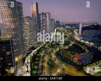 Atemberaubende Langzeitbelichtung von einer Drohne, die die beleuchtete Skyline von Santa Fe und La Mexicana Park in Mexiko-Stadt unter einem lila Abend zeigt Stockfoto