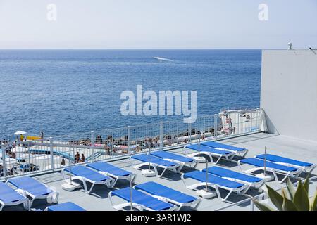 Blick auf mehrere leere Liegestühle im öffentlichen Poolbereich von ​​Lido. Funchal, Insel Madeira, Portugal Stockfoto