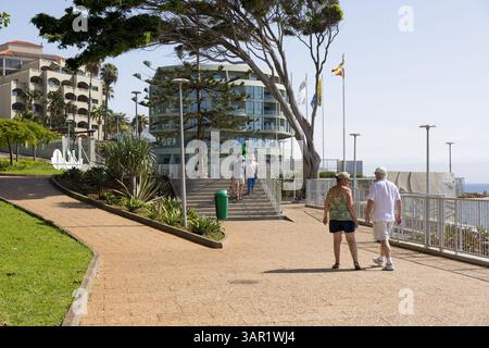 Funchal, Portugal - 05.10.2024: Seniorinnen und Senioren machen einen Spaziergang durch die Lido Promenade entlang der Küste. Funchal Stadt, Madeira Insel. Stockfoto