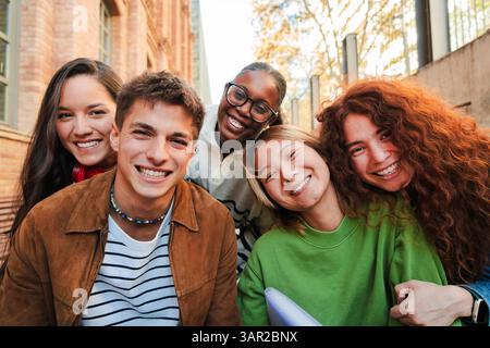 Eine fröhliche und lebhafte Gruppe junger Studenten, die sich gegenseitig amüsieren, während sie für ein lustiges Porträt posieren. Sie teilen Lächeln und Lachen und verkörpern das Wesen von Freundschaft und Kameradschaft. Stockfoto