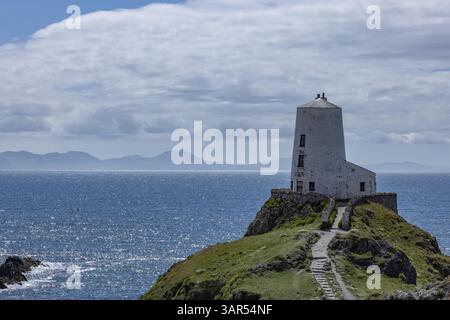 TWR Mawr Lighthouse, weißer Leuchtturm auf einem Hügel am Meer mit blauem Himmel und Wolken, Ynys Llanddwyn, Newborough, Anglesey, Wales, Großbritannien Stockfoto