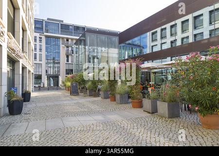 Grünanlage um einen Außenverpflegungsbereich zwischen modernen Gebäuden am Postplatz, im Hintergrund der Denkraum Sophienkirche, Dresden, Sachsen Stockfoto