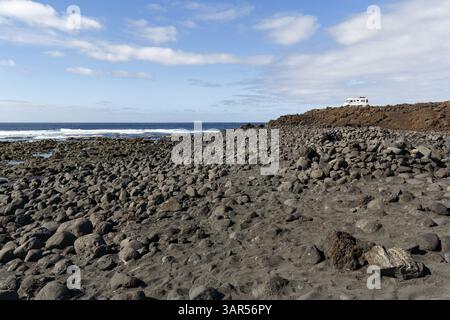 Playa de Janubio, schwarzer Lavastrand, vulkanisches Gestein, Wohnmobil am Horizont, Küste, Salinas de Janubio, Lanzarote, Kanarische Inseln, Spanien, Europa Stockfoto