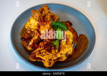 Hühnchen- und Waffelgericht mit Gewürzen darauf Stockfoto