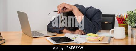 Geschäftsmann, es wird viel Arbeit aufgehäuft, es ist stressig. Überarbeiteter Geschäftsmann mit Schlafstörung, der am Schreibtisch schläft Stockfoto