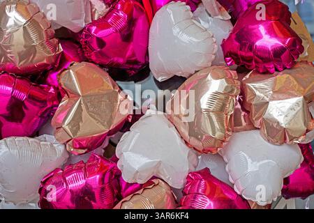 Aufblasbare glänzende Ballons in Herzform. Festlicher Hintergrund Stockfoto