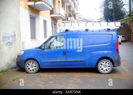 Cremona, Italien 15. April 2025 Blue Fiat Doblo Cargo, ein leichtes Nutzfahrzeug, das auf einer Stadtstraße mit einer Leiter am Dachträger geparkt ist, lesen Stockfoto