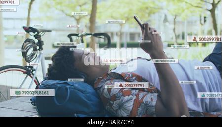 Bild von Social-Media-Symbolen und Zahlen über einem lächelnden Mann mit Smartphone Stockfoto
