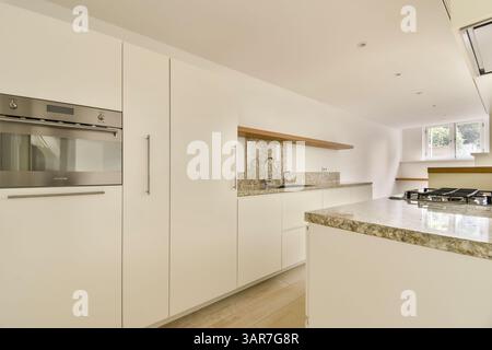 Eine moderne Küche mit eleganten Schränken, eleganten Arbeitsflächen und einem gut organisierten Layout, perfekt für kulinarische Kreationen und Versammlungen. Stockfoto