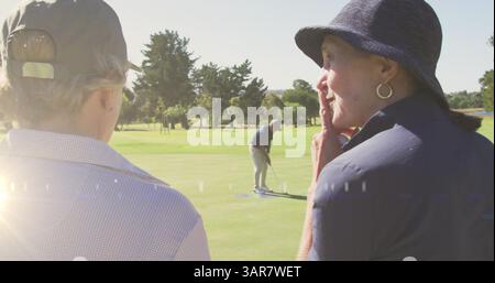 Bild von Lichtspuren über älteren kaukasischen Paaren auf dem Golfplatz Stockfoto