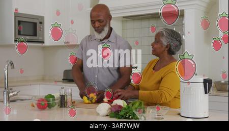 Das Bild von Erdbeeren gegenüber älteren, vielfältigen Paaren, die zu Hause Essen zubereiten Stockfoto