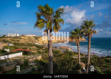 Sagres, Algarve, Portugal - Palmen am Stadtstrand Praia da Mareta, mit dem Aussichtspunkt Ponta da Atalaia im Hintergrund. Stockfoto